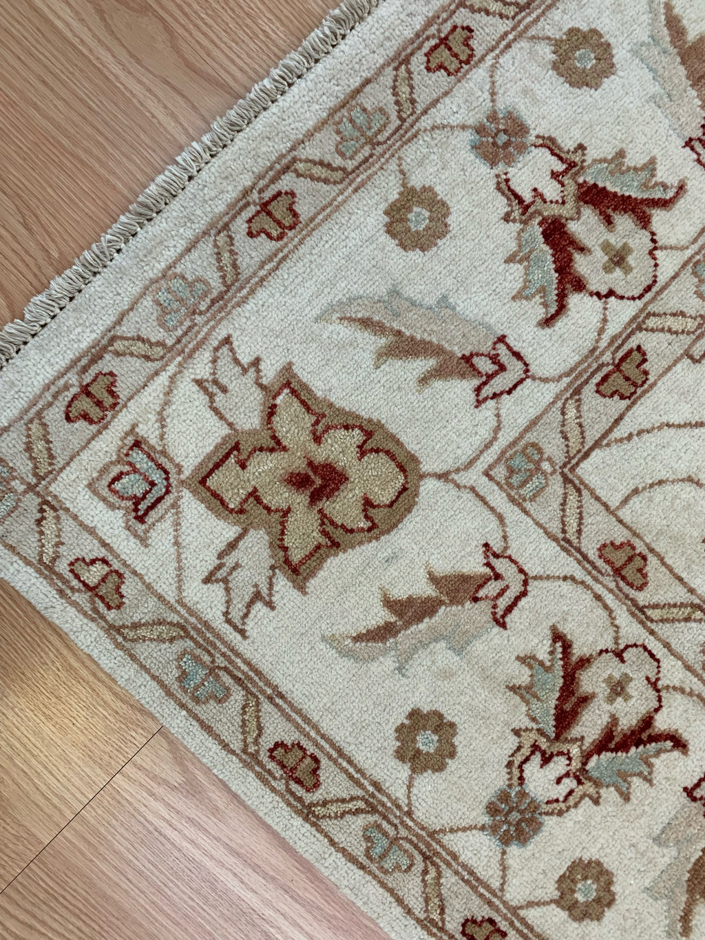 corner of 6’7"x9’4” hand-knotted wool Oushak rug in ivory