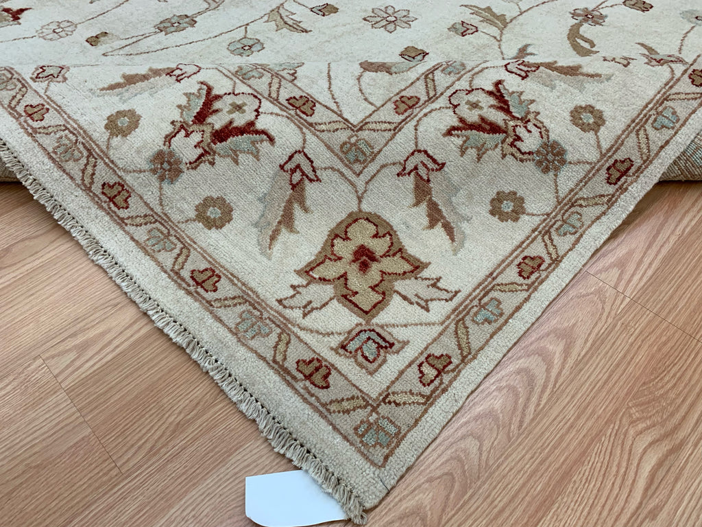 Folder corner of 6’7"x9’4” hand-knotted wool Oushak rug in ivory