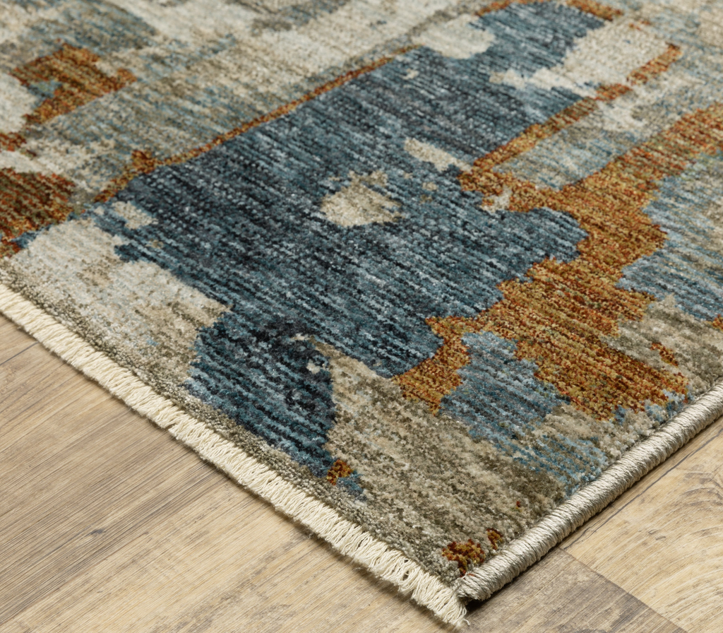 Close-up of a patterned rug with blue, brown, and beige colors on a wooden floor.